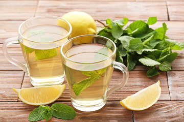Cup of tea with mint leafs and lemons on wooden table