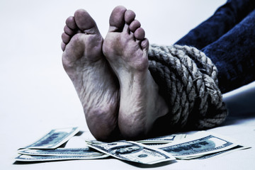 The legs of a woman bound by the rope and the money as symbol of kidnapping, human traffick and...