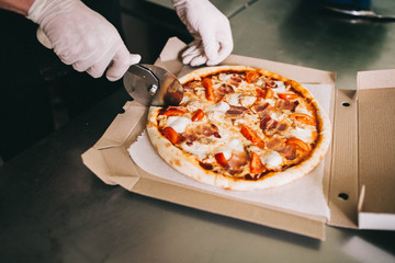 Man's hands cut ready pizza in a cardboard box - 193347989