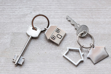 Two House key and keychain in the form of homes lies on wooden boards. Concept for real estate, mortgage, moving home or renting property.