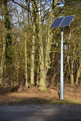 Pole with a solar panel standing on the edge of the forest.