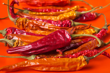 Dry chili pepper is lined up on an orange background