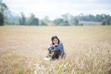 Naklejka na ściany i meble Asian woman sitting on the grass field outdoor travel