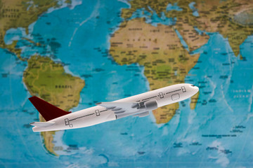 Traveling, tourism, international flights with flying airplane model and worldmap, close-up. White toy plane on the world map background. Travel concept
