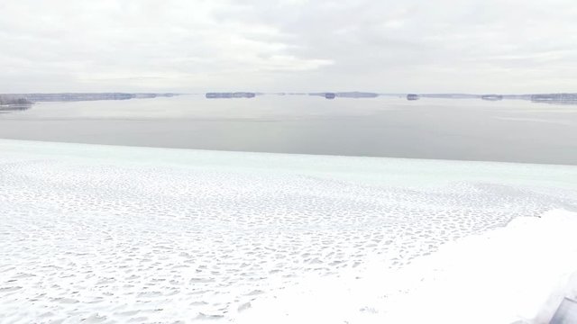 Flying backwards over wooden boathouses by a freezing lake