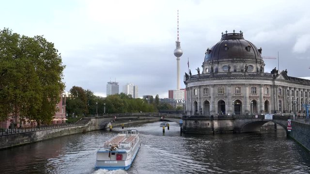 an afternoon shot of tour boats on a river and museum island in berlin, germany