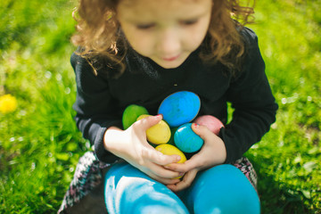 The girl is holding a collection of colorful Easter eggs.