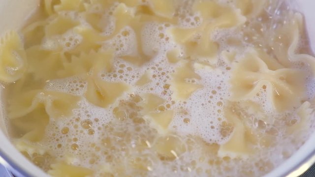 Boiling pasta in a saucepan. Farfalle - bow shaped pasta 
