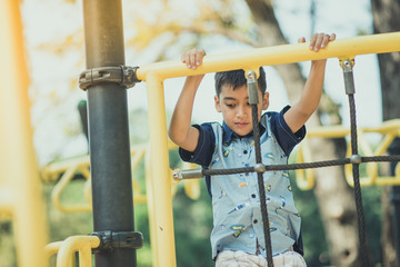 Obraz premium Little boy climbing up on the rope at playground