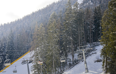 Chairlift at Italian ski area on snow covered Alps and pine trees