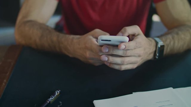 Male hands using phone. Close up of man hand scrolling on mobile phone. Male hand typing message on phone in office. Mobile communication concept