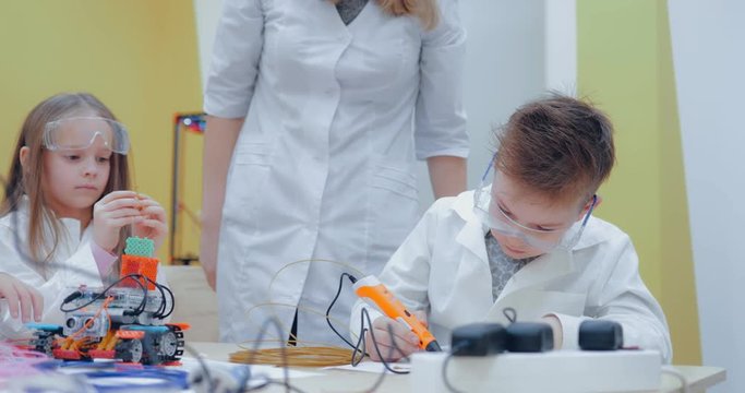Schoolboy drawing on paper with 3D pen. Class of robotics