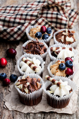 Chocolate  mini cupcakes with chocolate and berries on wooden table