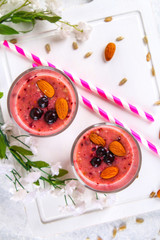 Blueberry smoothies of berries, banana and almonds in glasses with cocktail tubes on a white wooden board.