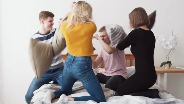 Teens fighting pillows in bedroom