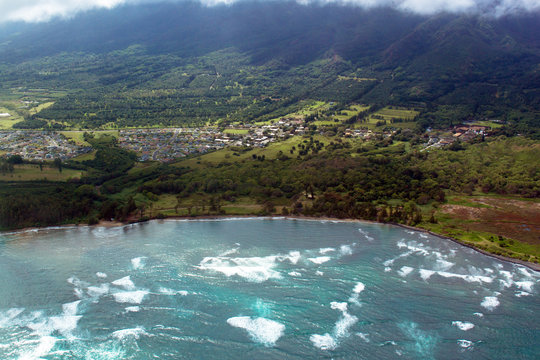 Aerial view of surf rolling across Kahului Bay beside the town of Kahului on the island of Maui, Hawaii, shot from a small, low-flying prop plane