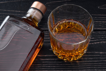 Bottle of whiskey on a  black wooden table.Top view.