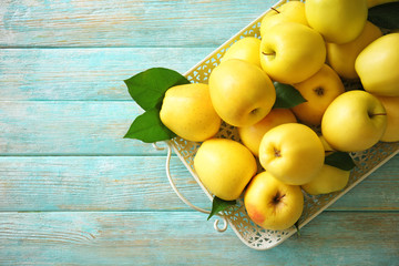 Tray with ripe yellow apples on wooden background