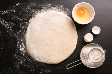 Raw dough with ingredients on kitchen table