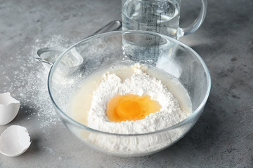 Glass bowl with ingredients for dough on kitchen table
