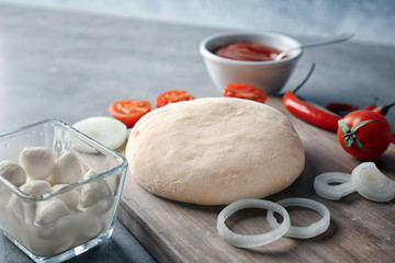 Raw dough with ingredients for pizza on kitchen table