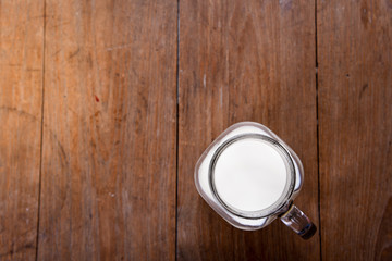 top view image milk in a jug and a glass  on wooden table.