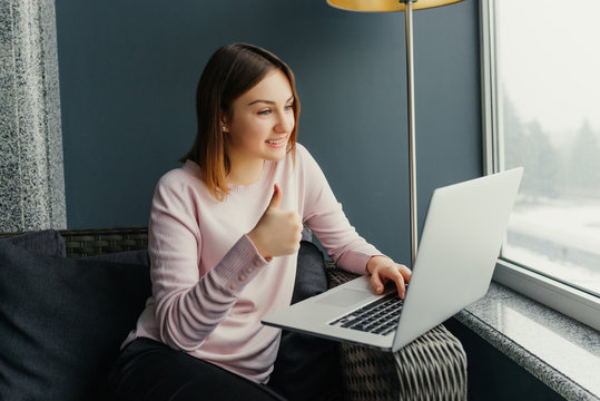 Smiling young woman using laptop and making video call in cafe