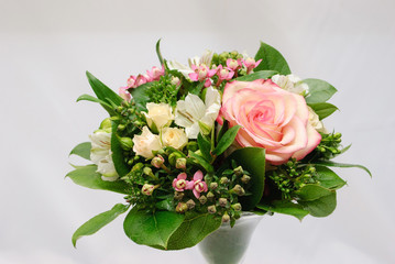 greeting bouquet of rose bush, alstroemeria, bouvardia and salal in glass vase on white background