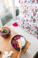 Wodden Table with Fruit Smoothies Bowl. Banana, Coconut Flakes, Strawberries, Dragon Fruit and Granola. The Inscription 