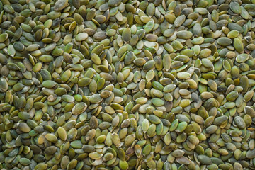 Green background of pumpkin seeds.