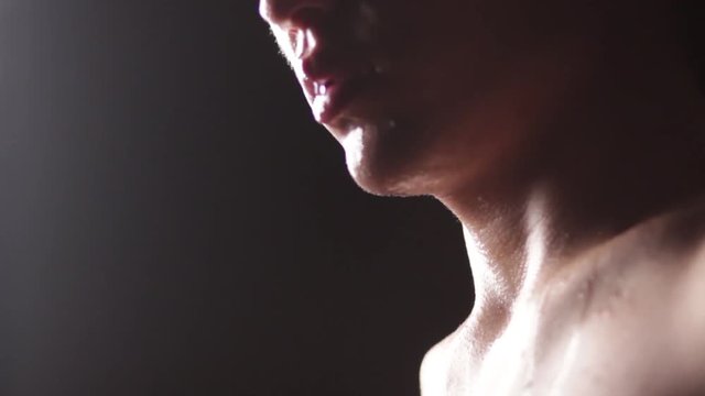 The lower part of the face of an Asian man in a spray of water. Drops on the nose, lips and chin. Close-up.