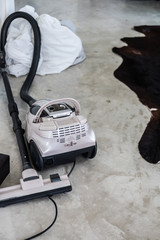 Vacuum cleaner on a grey concrete floor. Bed sheet washing. House cleaning concept.
