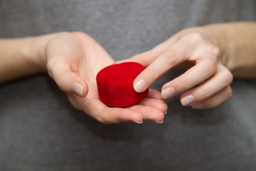 young woman's hands holding a red heart-shaped box