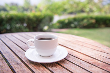 Hot coffee on wooden table with nature background