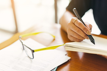 Asian stylish glasses woman designer wear black dress and red lips happiness writing a notebook in selective focus..