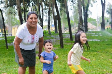 Fototapeta na wymiar Happy latin family - mother with her two little children having fun in the summer park.