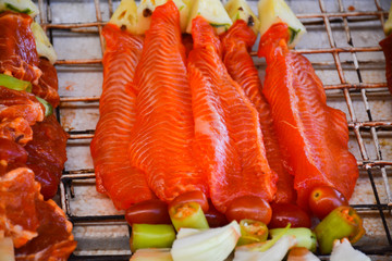 marinated fish with vegetables on sticks on the grill