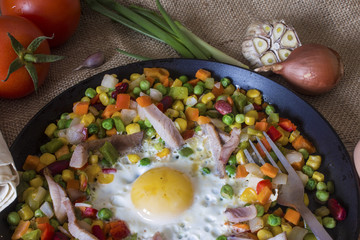 delicious hot vegetable mixture in a frying pan with fried scrambled eggs close