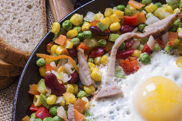 hot appetizing breakfast with fresh, varied sliced vegetables in a frying pan with fried egg