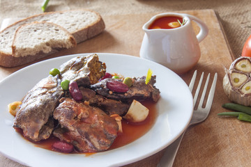 Moroccan dish of fried chicken hot liver in a plate with a spicy vegetable sauce on the table