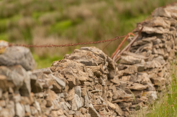 Rusty barbed wire stretched over drystone wall