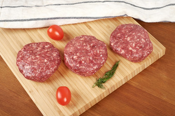 Raw cutlet of minced meat on a wooden cutting board.