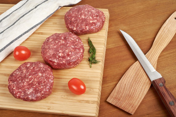Raw cutlet of minced meat on a wooden cutting board.