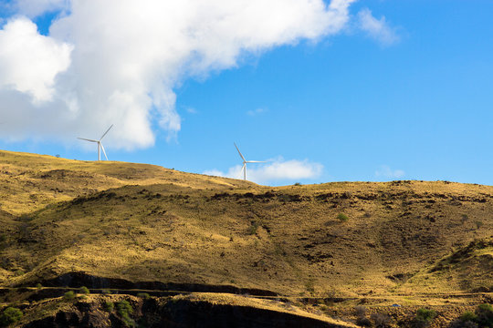 A wind farm rises above Honoapillani Highway 30 as it passes along Papawai Point on the northwest coast of Maui, shot from a boat on the open water