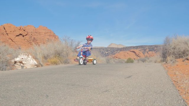 Little boy on a tricycle in red rock country. 