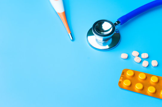 .Doctor office desk with medical blister of capsule pills red injection syringe and stethoscope.
