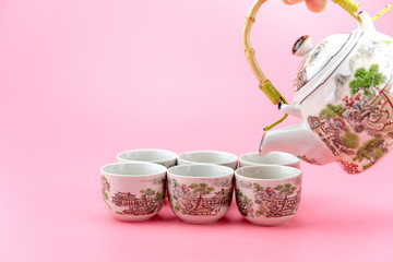 Teapot with cups on a pink background.