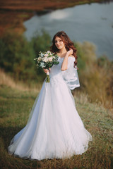 Fototapeta na wymiar beautiful bride with stylish bouquet on the background of the lake