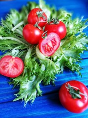 помидоры черри и зеленый салат на синем деревянном фоне