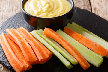 fresh raw celery and carrots  and cheese cream sauce dip close-up. horizontal
